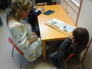 Maestra Stefania legge un libro illustrato a una piccola paziente